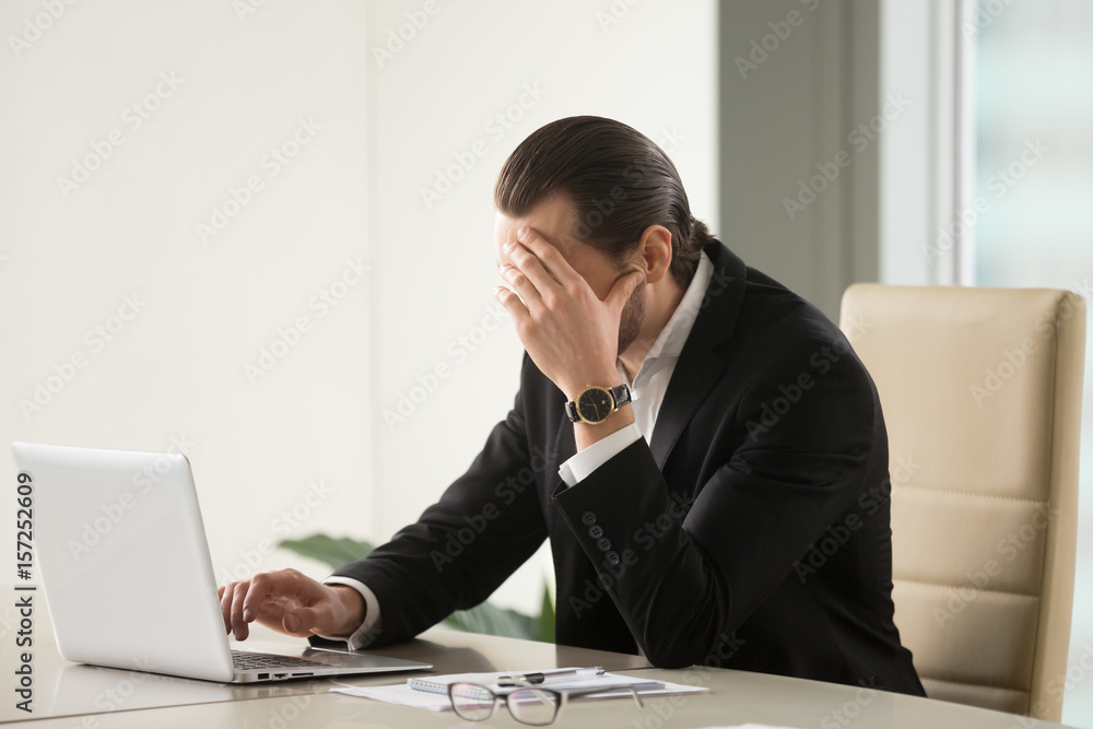 Tired businessman at desk with laptop searching way out from difficult situation. Thoughtful stressed frustrated man working for too long on computer, chooses solution, thinking about hard problem Tired businessman at desk with laptop searching way out from difficult situation. Thoughtful stressed frustrated man working for too long on computer, chooses solution, thinking about hard problem
