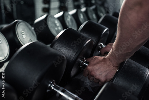 partial view of man taking dumbbells for exercising at gym