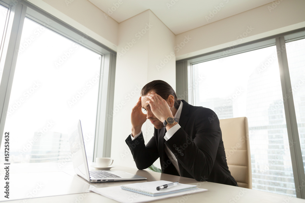 Stressed businessman at desk holding head in hands looking on pc laptop screen. Tired entrepreneur exhausted with too long work. Executive hard thinking about difficult problem, worried about result Stressed businessman at desk holding head in hands looking on pc laptop screen. Tired entrepreneur exhausted with too long work. Executive hard thinking about difficult problem, worried about result