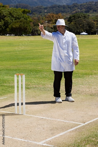 Foto Full length of cricket umpire signaling out during match