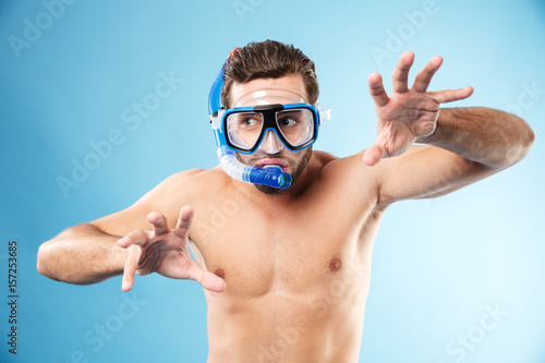 Young funny man playing with hands and wearing water mask