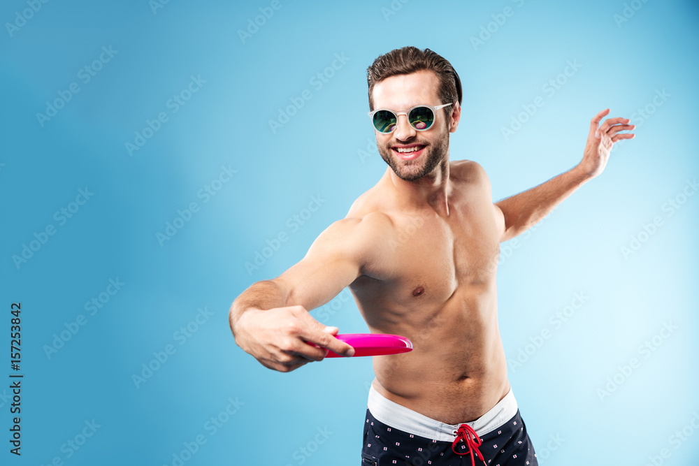 Smiling cheerful man in summer shorts playing frisbee Smiling cheerful man in summer shorts playing frisbee