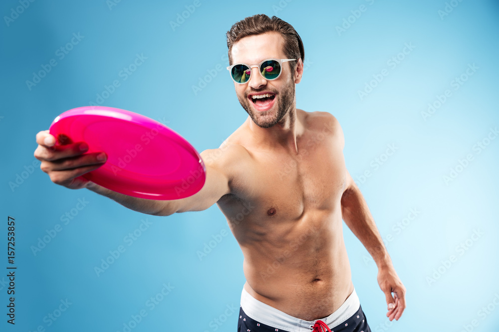 Active young man in summer clothes throwing frisbee disc