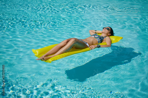 A woman in the pool floats on a blown mattress