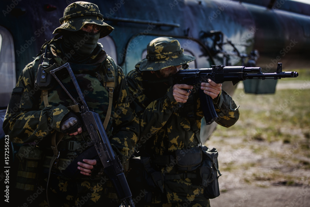 Obraz premium Photos of a group of military men with a gun in front of a helicopter