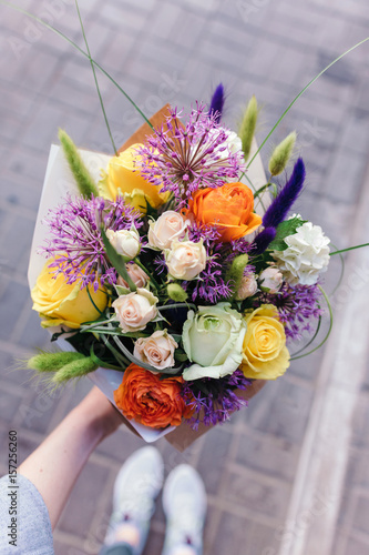 Stylish bouquet in orange and purple colors. Bouquet of rose and ranunculus flowers in woman's hand