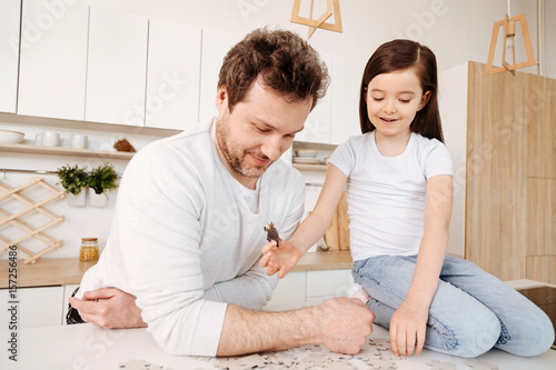 Single-parent family spending time together while doing puzzle