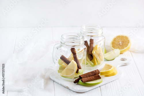 Two glass jars with ingredients for infused water on wooden board Detox fruit water Copy space