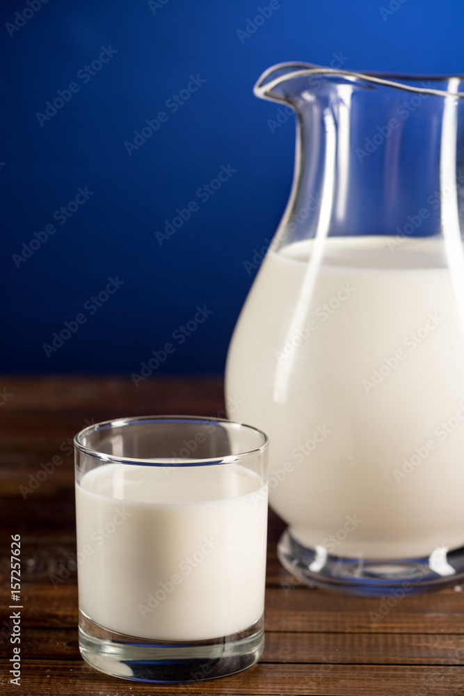 Close-up view of fresh organic milk in glass jug and glass on wooden table top Close-up view of fresh organic milk in glass jug and glass on wooden table top