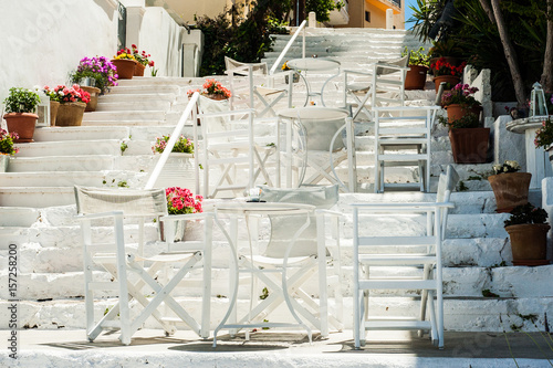 Obraz na płótnie White Greek stairs with tables and chairs. Typical Greek street with flowers w salonie