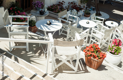 Obraz na płótnie White Greek stairs with tables and chairs. Typical Greek street with flowers w salonie