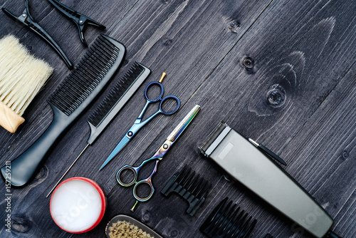 Hairdresser tools on wooden background. Top view on wooden table with scissors, comb, hairbrushes and hairclips, free space. Barbershop, manhood concept
