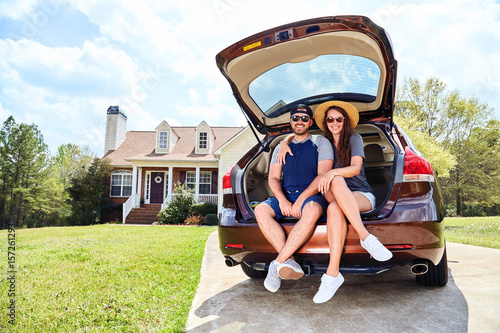 Couple, men and woman sitting in cars trunk and smiling photo