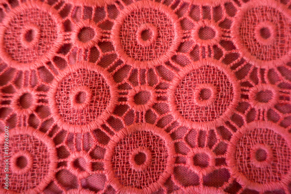 Close up of coral red open embroidery with circular eyelets Close up of coral red open embroidery with circular eyelets