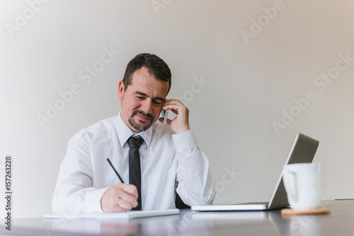 Portrait of a smiling middle aged businessman with beard, working at home on some project.