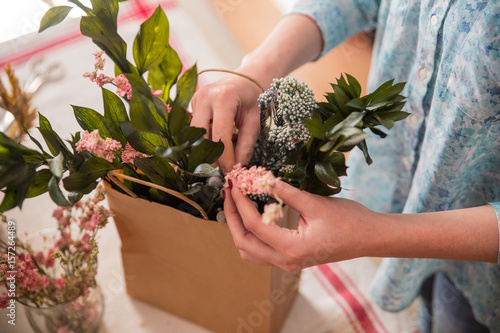 Crop person composing flowers in bag photo