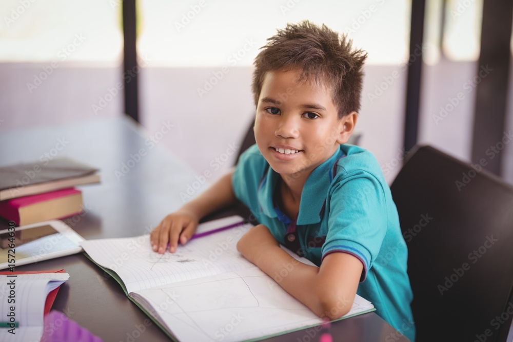 Portrait of smiling schoolboy doing his homework in library Portrait of smiling schoolboy doing his homework in library