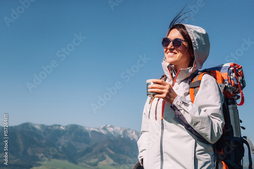 Woman traveler drinks tea on the mountain top