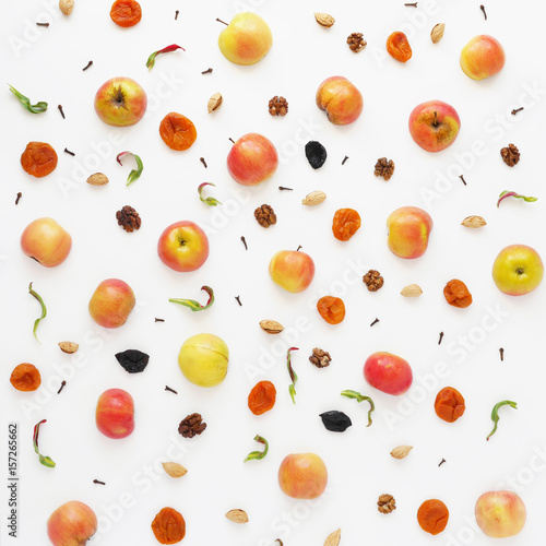 Fruit pattern of apples on a white background. Food background. Food collage of red apples, nuts and dried fruits: dried apricots, prunes.