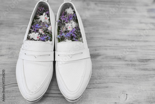 Women's white shoes and flowers inside