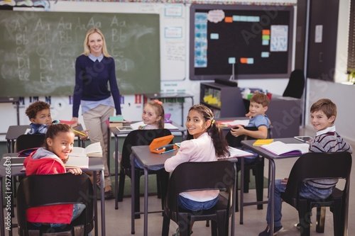 Portrait of smiling teacher and schoolkids in classroom