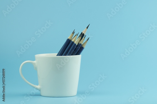 pencils in white cup on blue background and copy space