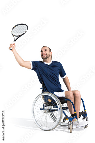 Disabled young sportsman in wheelchair playing tennis and smiling isolated on white