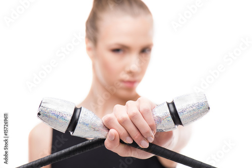 Canvas Print rhythmic gymnast in bodysuit posing with clubs and looking at camera isolated on