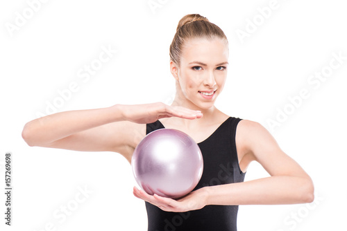 attractive rhythmic gymnast in bodysuit smiling and holding ball isolated on white