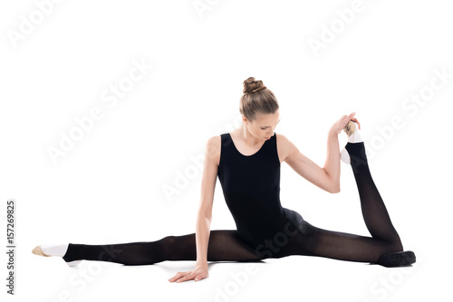 Athletic young rhythmic gymnast in sportswear stretching isolated on white