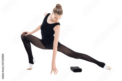 Athletic young rhythmic gymnast in sportswear stretching isolated on white