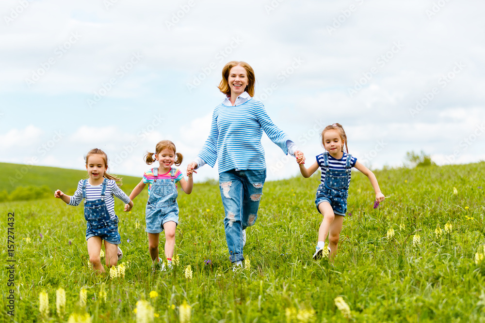 Happy family mother and children daughter girls laughing and running on meadow in summer Happy family mother and children daughter girls laughing and running on meadow in summer
