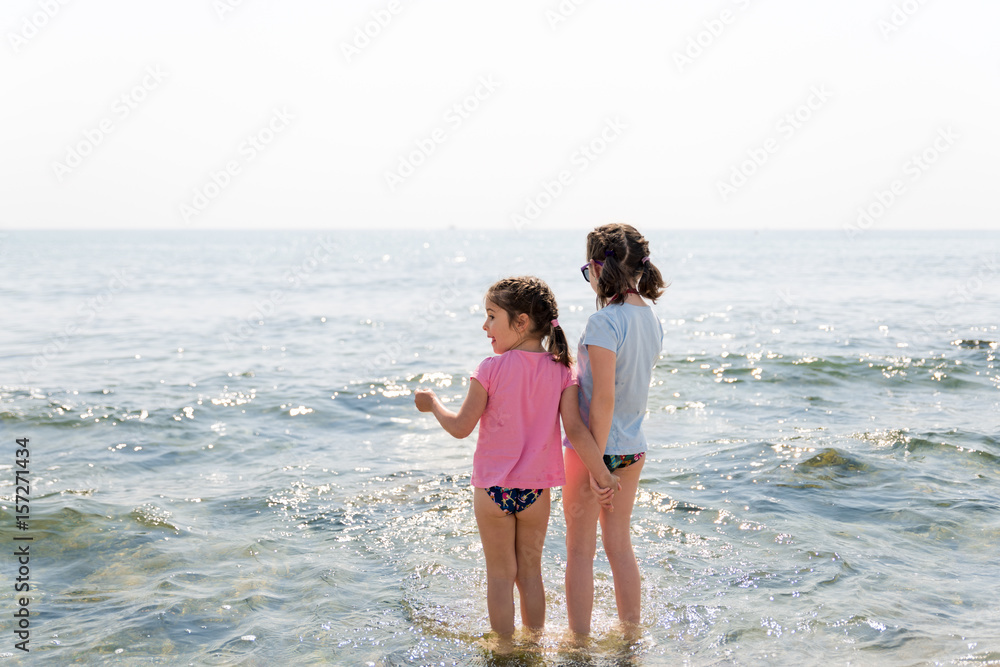 Sisters playing on the beach and holding hands. Sisters playing on the beach and holding hands.
