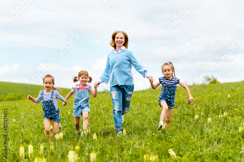 Happy family mother and children daughter girls laughing and running on meadow in summer