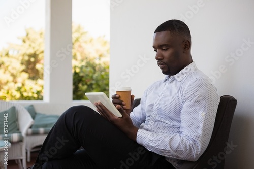 Businessman using digital tablet while drinking coffee in cafe