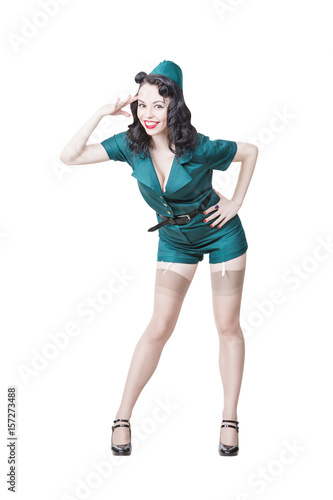 Portrait of Cute Sexy Brunette with black hair. Pin up Female Dressed in military clothing Uniform and Garrison cap saluting. Army Pin-up Girl Concept