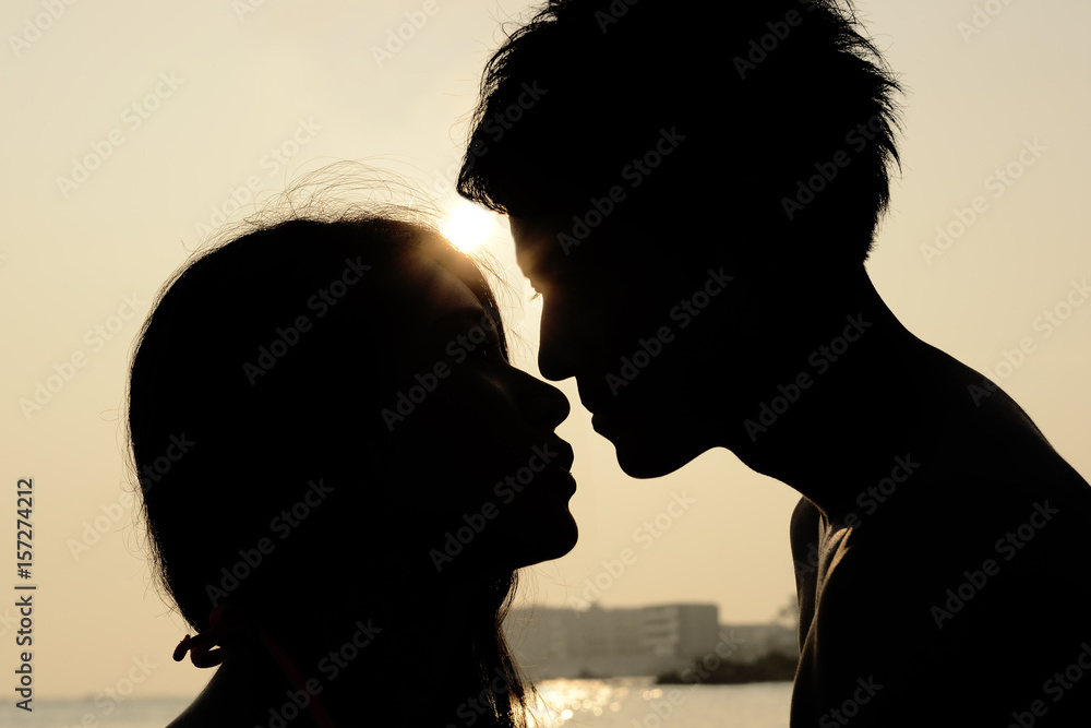 夕日の海でキスをするカップル