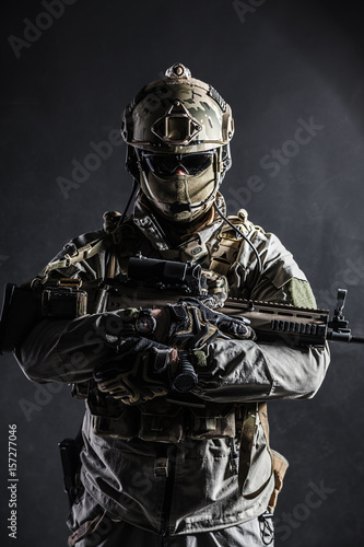 Army soldier in Protective Combat Uniform holding Special Operations Forces Combat Assault Rifle. Studio shot, dark contrast, cropped, black dark background © Getmilitaryphotos