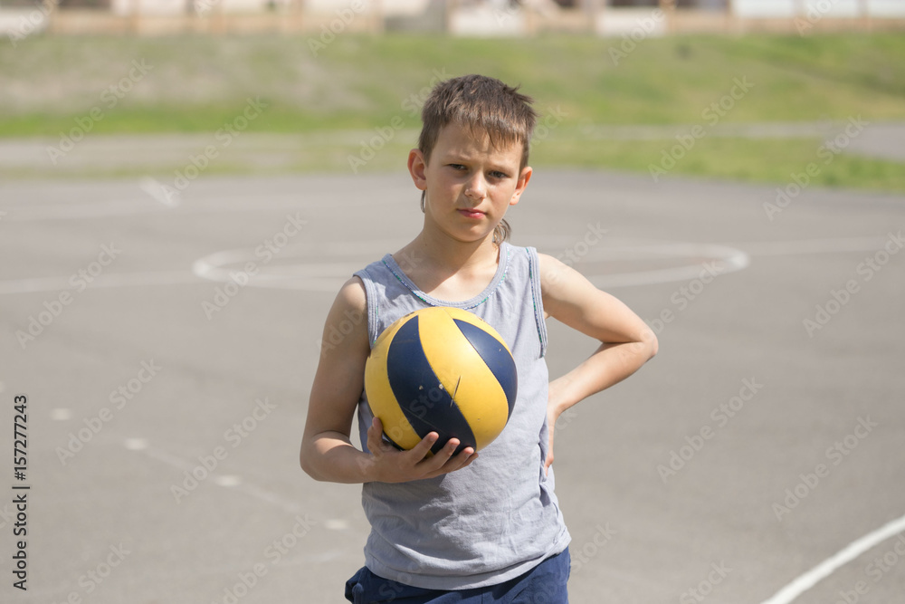 A teenager in a vest holds a ball in his hand