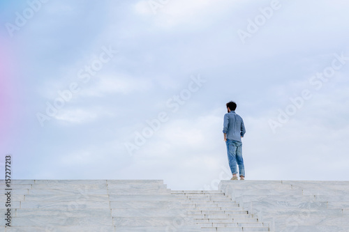 Young man stands alone on top of some steps