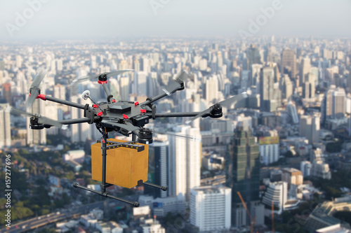 Drone transport flying with cardboard box above city, futuristic delivery concept