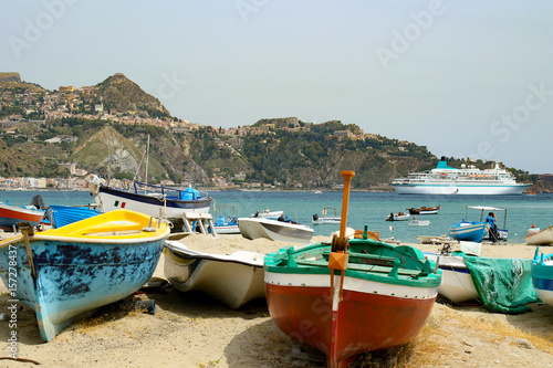 Bunte Fischerboote am Strand von Giardini-Naxos mit Kreufahrtschiff im Hintergrund  Sizilien 