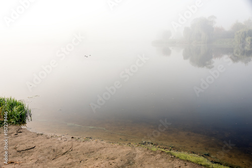 Morning mist over the lake with reflection in the water. Fog on a river