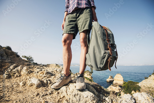 Hiker traveler woman holding backpack on a hiking trail, travel and active lifestyle concept