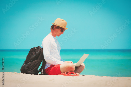 man working on laptop at tropical beach