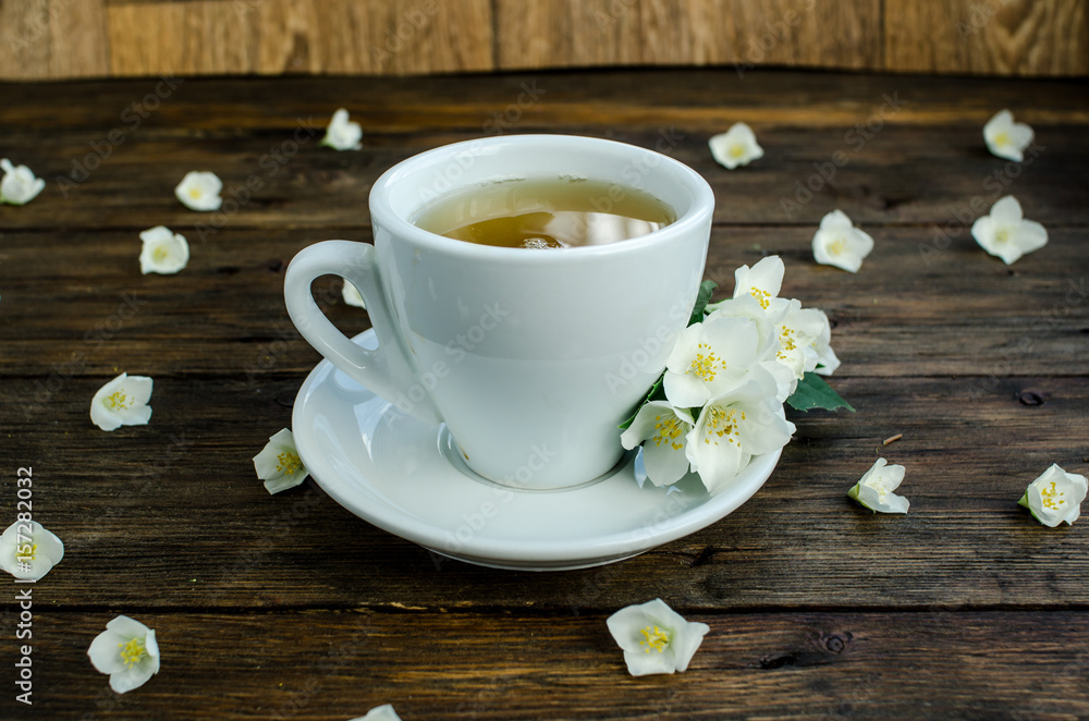 Obraz premium jasmine tea with jasmine flowers on wooden background
