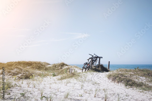 Fototapeta Naklejka Na Ścianę i Meble -  bicycles parked at wooden fence in grass covered dunes at baltic sea beach in northern Germany