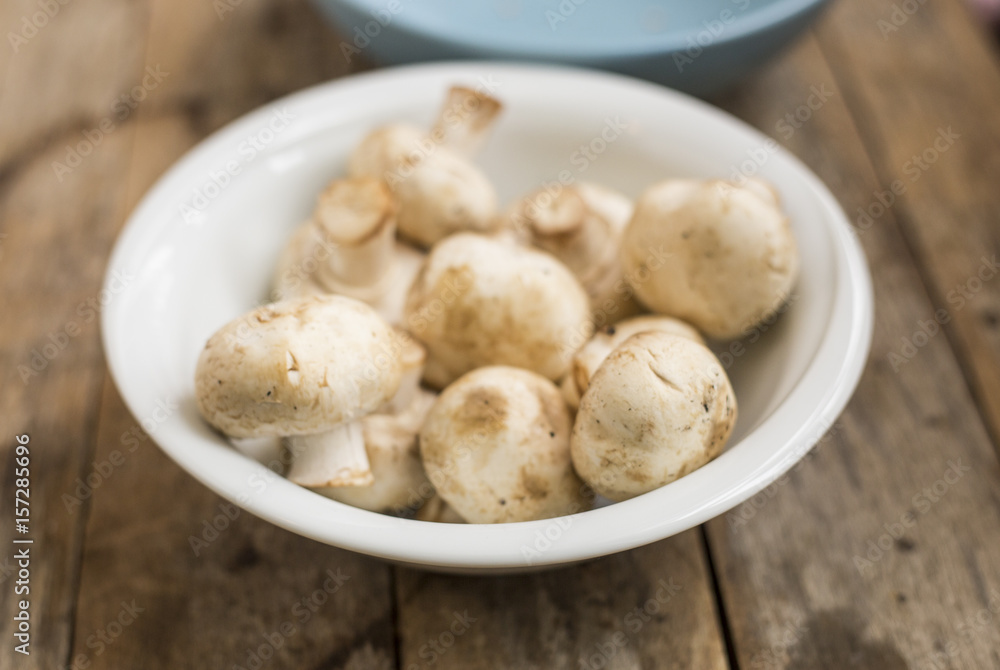 Raw mushrooms in a bowl on a wooden table Raw mushrooms in a bowl on a wooden table
