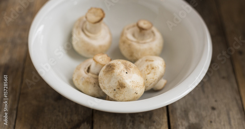 Raw mushrooms in a bowl on a wooden table