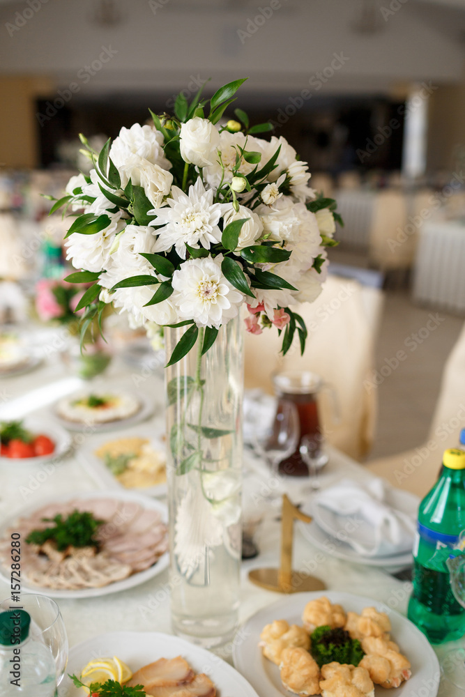 White bouquet stands in the center of dinner table